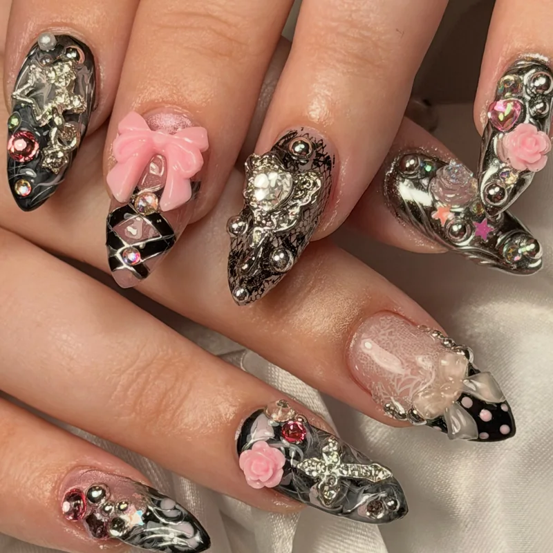 Sculptural silver nail art with pink bows, tiny gems, black accents, and translucent pink details.