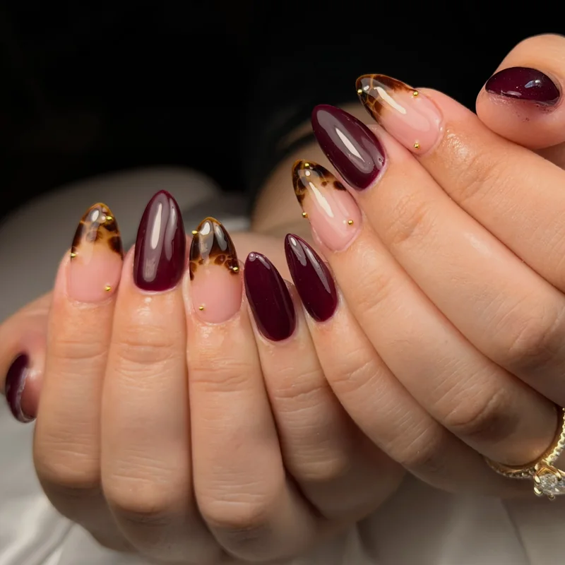 Glossy burgundy almond nails paired with sheer pink nails and warm tortoiseshell tips.