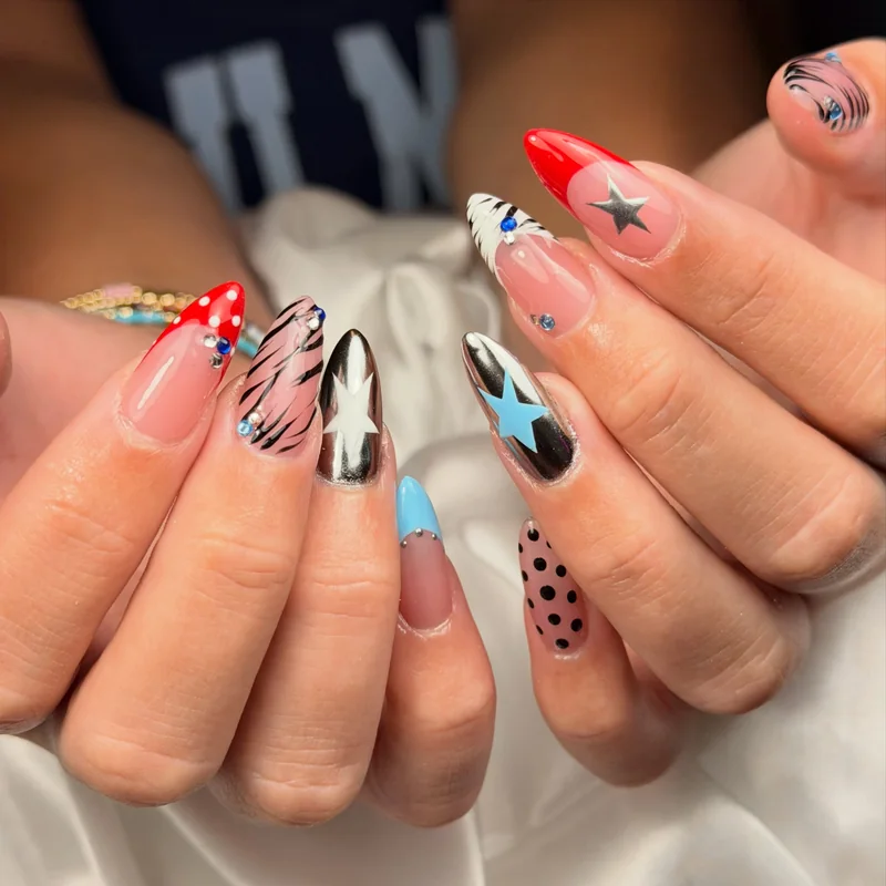 Almond nails combining silver chrome stars, red and blue French tips, zebra stripes, dots, and tiny crystals.
